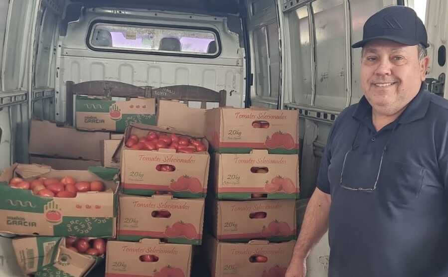 Persona posando junto con carga de tomates.