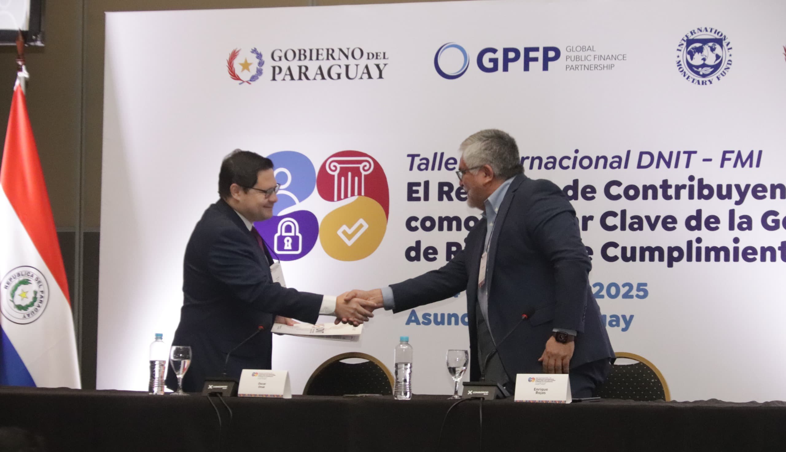 El director nacional Óscar Orué saludando al economista sénior del FMI, Enrique Rojas.